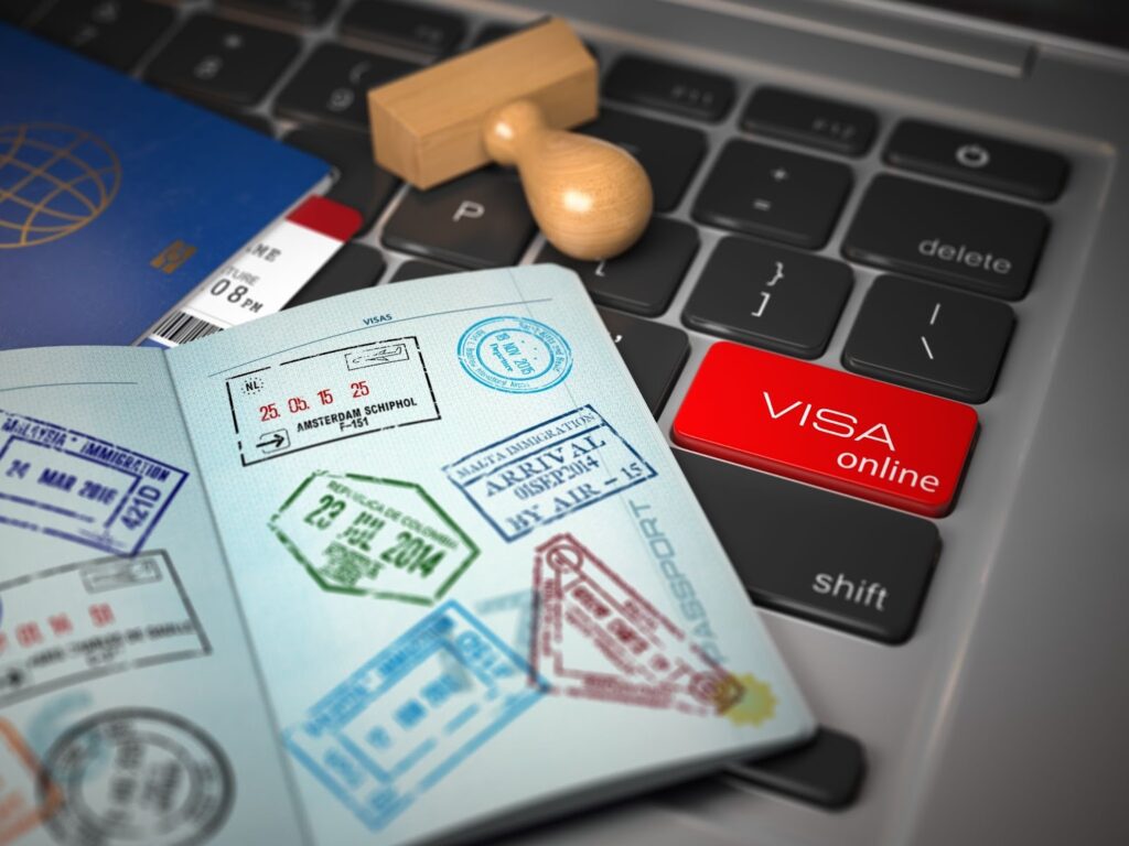 Open passport with multiple visa stamps resting on a laptop keyboard