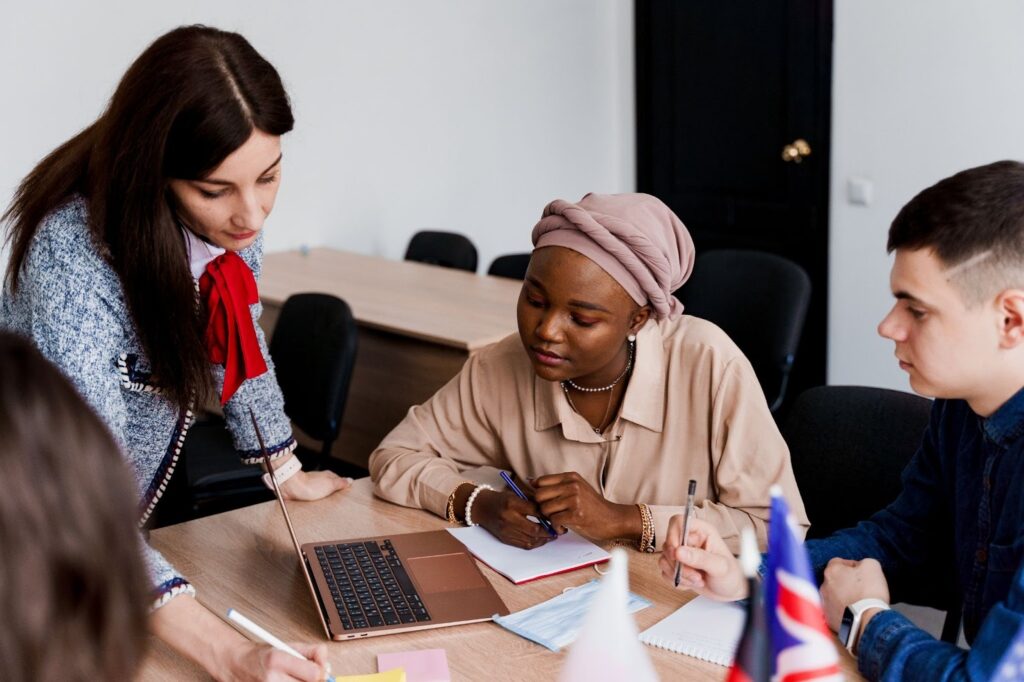 Asylum seekers attending a language learning class, using laptops and teamwork to support integration and resettlement
